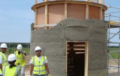 A student stands in front of a half-finished hempcrete tower