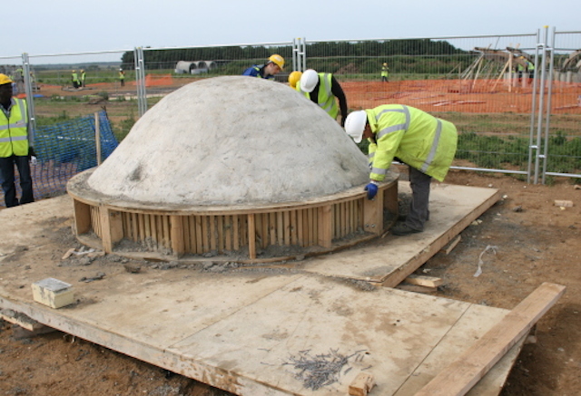 A site operative smoothes wet concrete in dome-shaped formwork