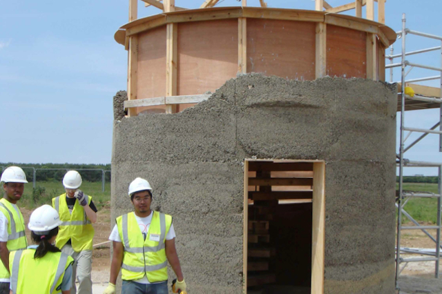 A student stands in front of a half-finished hempcrete tower
